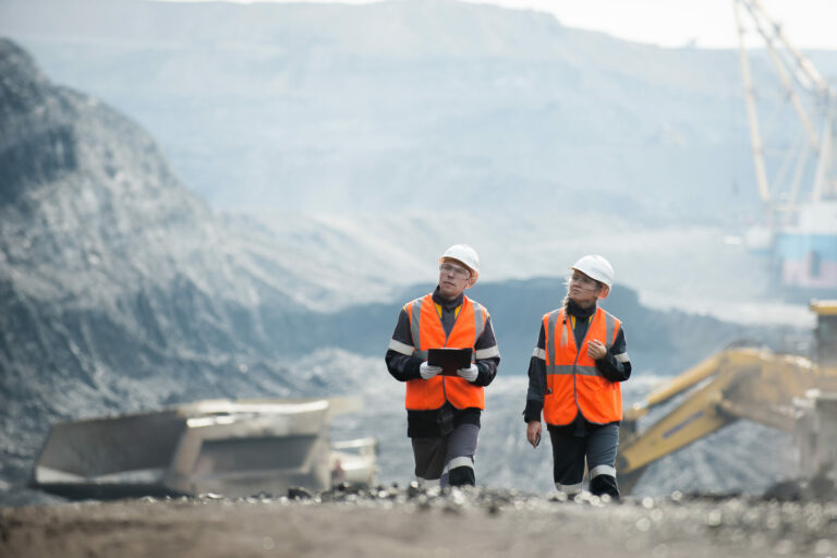 Two speacialists examining coal at an open pit